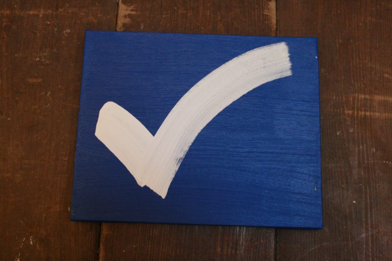 A white checkmark on a blue wooden panel